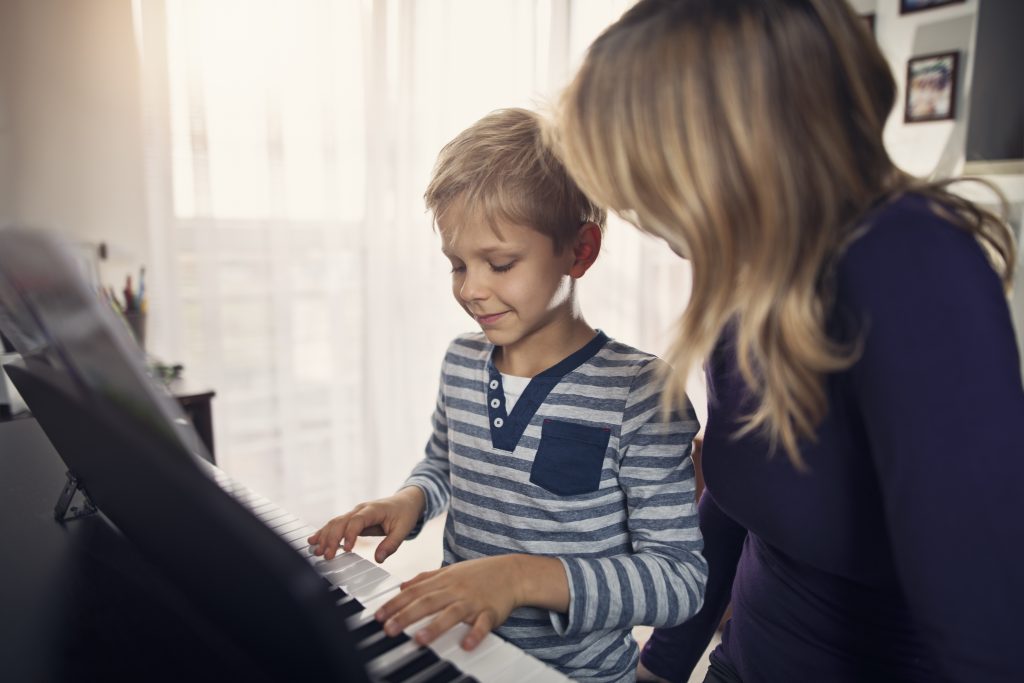 Little boy practicing piano with mother 932675862 8256x5504